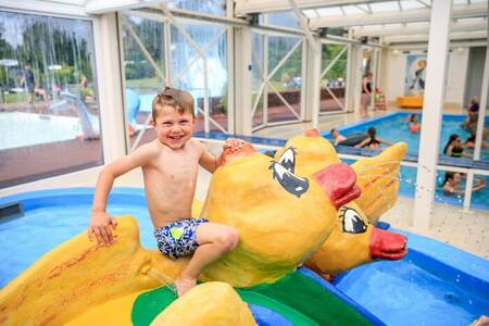 Child on play equipment in the indoor paddling pool of the Topparken Resort Veluwe holiday park