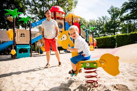 Child on a seesaw in a playground at the Topparken Résidence De Leuvert holiday park