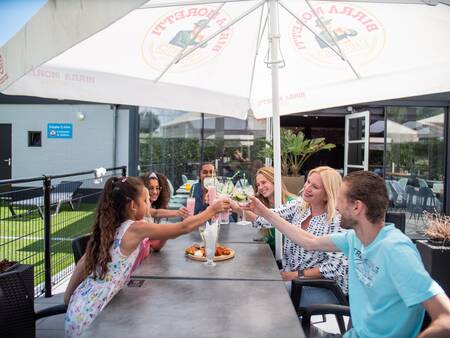 The family enjoys a drink on the terrace of the restaurant of Topparken Résidence De Leuvert