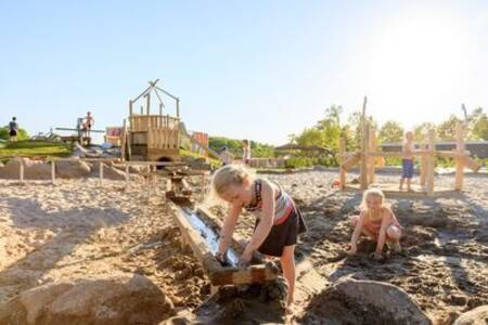 Children play with water and sand in the playground of holiday park Ackersate