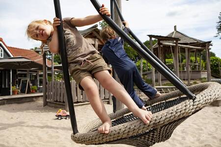 Children on a swing in a playground at the Sandberghe holiday park