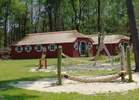 Holiday homes type "Boerderij Grand" next to a small playground at Veluwecamping De Pampel
