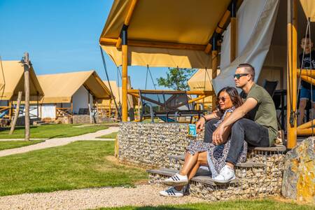 A couple sits in front of a glamping tent at the EuroParcs Poort van Maastricht holiday park